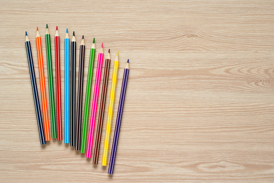 Pencils, crayons and notebook on a desk.