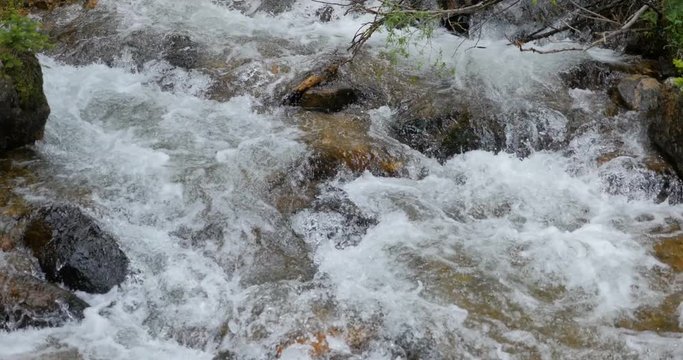 4k UHD stationary tight shot of beautiful natural water flowing over a cascade of rocks in a river in Rocky Mountain National Park, Colorado. 
