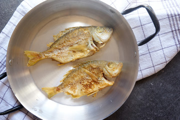Fried fish in an old pan on the table