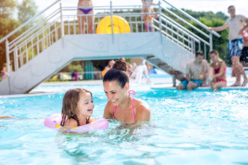 Mother and daughter in swimming pool, aquapark. Sunny summer.