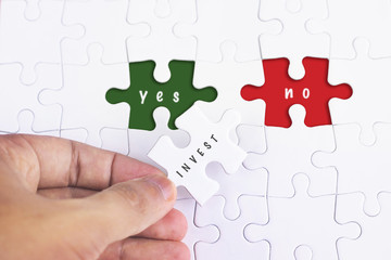 Business Concept - Female hand and missing puzzle with INVEST, YES NO WORD