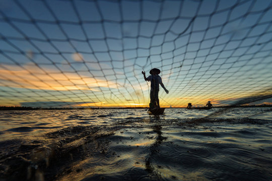 Fisherman throwing net in river during sunset