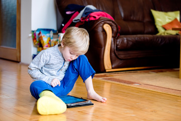 Boy with broken leg in cast playing on tablet.