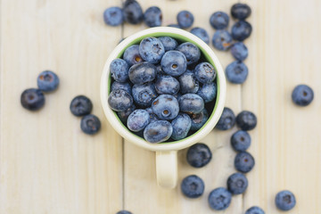 Mug filled with blueberries on white background.