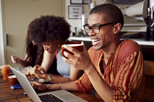 Man using laptop and holding coffee cup