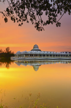 Beautiful white mosque during burning sunrise with mirror reflection on the lake