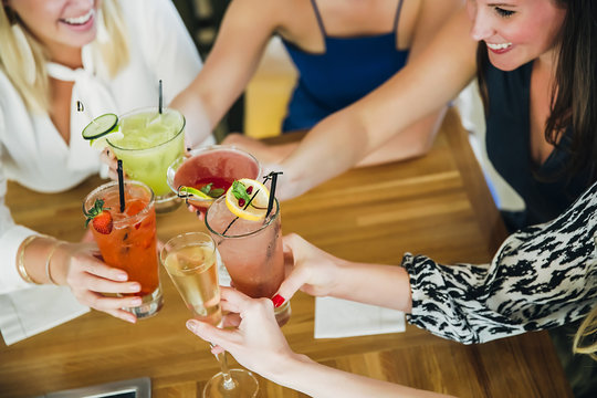 Women toasting at bar with cocktails
