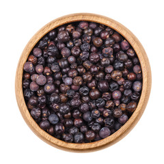 Juniper berries in a bowl on white background. Dried seed cones from Juniperus communis, a conifer, are used as spice and give gin its flavor. Isolated, macro photo and close up from above.