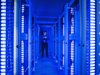 Black businessman using digital tablet in server room