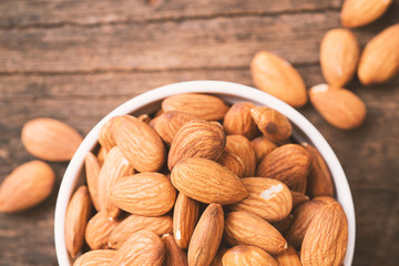raw almond in bowl on wooden table.
