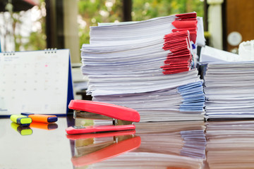 Stapler with pens and business documents stack on table
