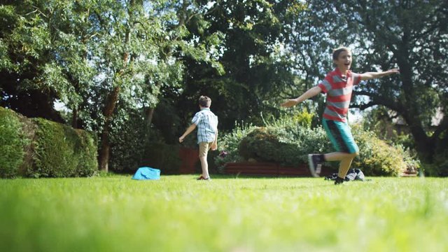  2 Active young boys playing soccer with their father in the garden. 