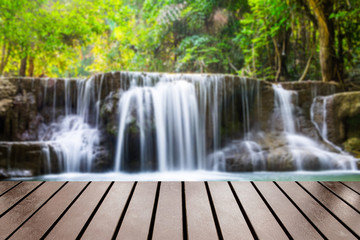 Wood table top on blurred waterfall tropical deep forest