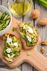 Bruschetta with french beans, green onions, feta cheese and walnuts, top view