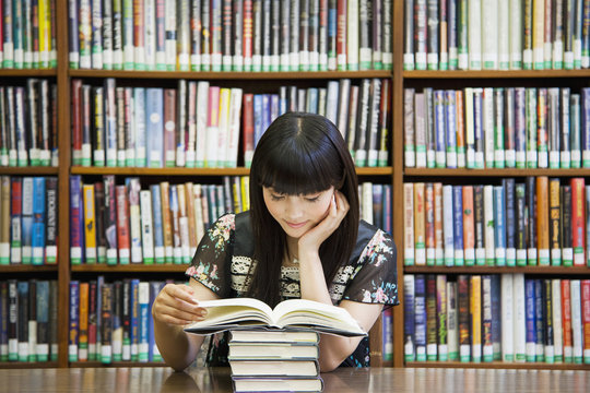 Smiling woman reading book in library