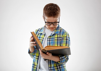 child boy teenager with glasses reding book on  gray background