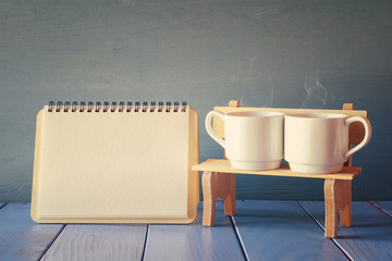 Couple coffee cups next to empty notebook