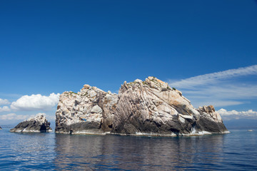 скалистый остров в море на фоне голубого неба и облаков © neonnspb