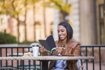 Indian woman reading booklet at outdoor cafe