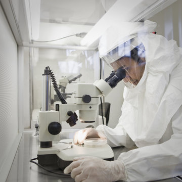 Middle Eastern scientist in clean suit using microscope