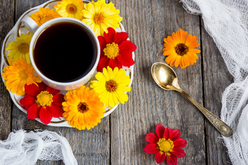 Flowers around cups of coffee. Wooden background