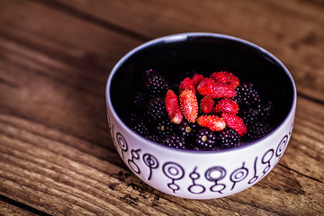 Mixed berries in plate on rustic wooden background. Close up, top view, high resolution product. Harvest Concept. Top view.