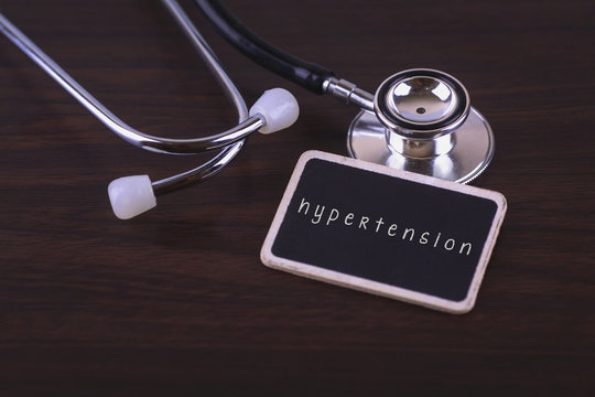 Stethoscope on wood background with hypertension words as medical concept