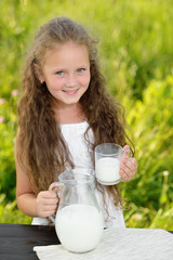 Adorable smiling girl having breakfast drinking milk outdoor summer