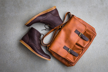 Men's casual outfits with brown boots and brown handbag on gray grunge background