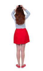 back view of standing young beautiful  woman.  girl  watching. Rear view people collection.  backside view of person. Long-haired brunette in red skirt anxiously holding his head.  