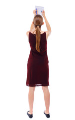 back view of  stands woman takes notes in a notebook. girl  watching. Rear view people collection.  backside view of person.  Isolated over white background. Slim blonde in a burgundy dress writes in