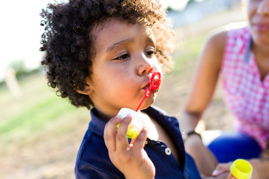 African american baby blowing soap bubbles in the park.