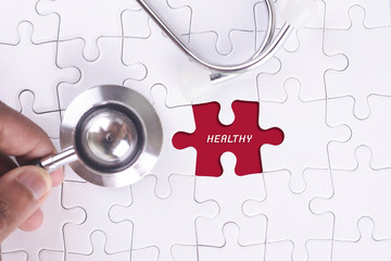 Medical Concept - A doctor holding a Stethoscope on  missing puzzle