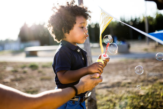 African american baby blowing soap bubbles in the park.
