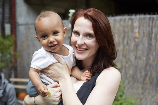 Smiling mother holding baby son in backyard