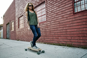 Mixed race woman riding skateboard on city street