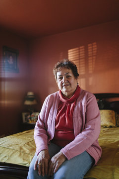 Hispanic woman sitting on bed