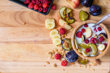 Bowl of muesli with berries, fruits and milk - good and healthy breakfast. Scattered ingredients and slices of fruits. view from above. space for text