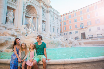 Fototapeta na wymiar Portrait of family at Fontana di Trevi, Rome, Italy. Happy parents and kids enjoy italian vacation holiday in Europe.