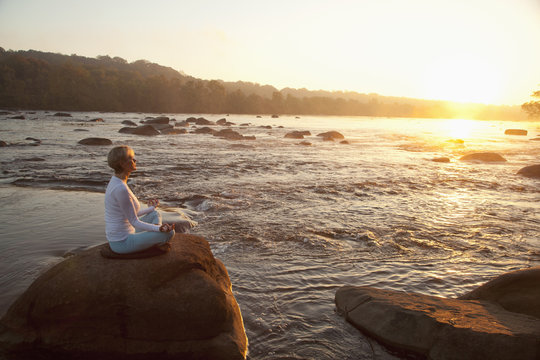 Woman practicing yoga on rock near ocean