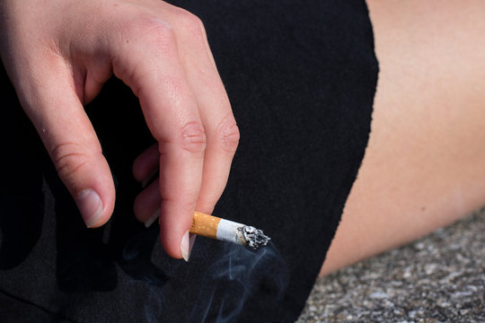 Frauenhand hält rauchende Zigarette