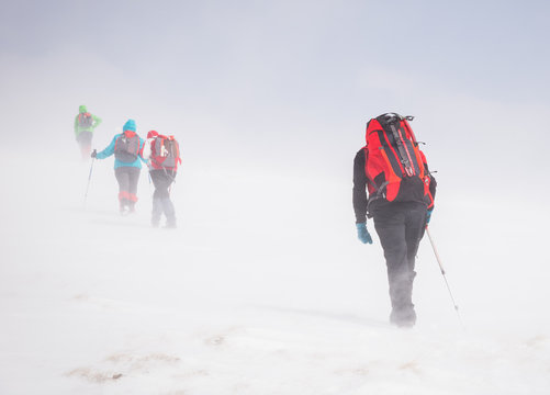 Group of people on Papusa mountain in winter season, hiking towards the top of Iezer peaks in Romania