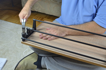 Hammering plastic holders on a drawer of a shoe cabinet