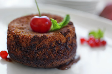Delicious fondant with cherry and red currant on plate, closeup