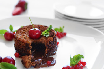 Delicious fondant with cherry and red currant on plate, closeup