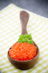 Salmon caviar with spoon on gray background.