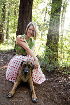 Mixed race woman and dog in forest
