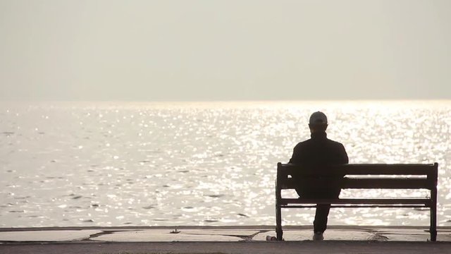 Lonely Man Sitting On The Bench at Beach 
