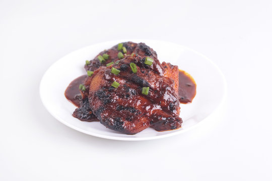 Grilled chicken or ayam golek on white plate, white background.