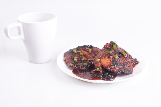 Grilled chicken or ayam golek on white plate, white background.